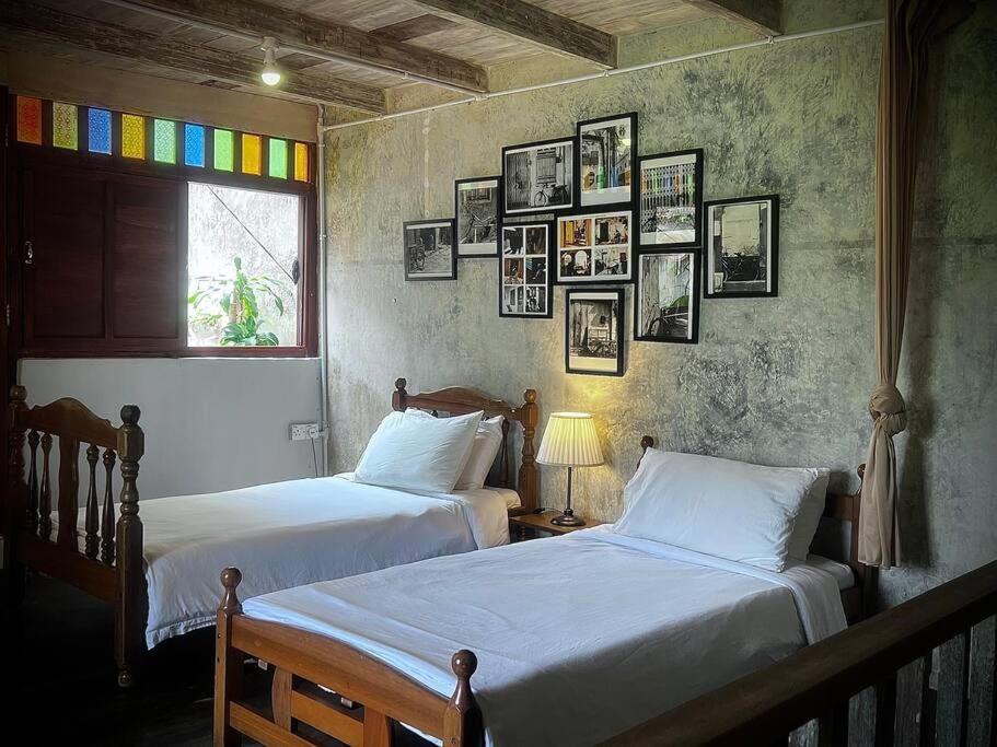 twee bedden in een kamer met foto's aan de muur bij LEJU 21 樂居 Explore Malacca from a riverside house in Melaka