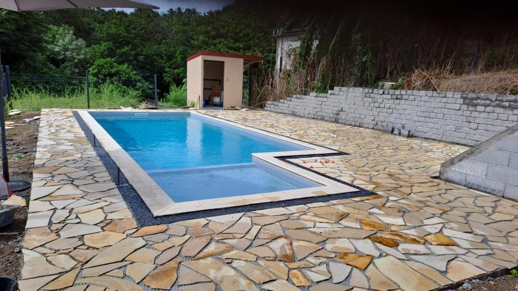 a swimming pool in a yard with rocks and a brick wall at La Kay Cassi in Saint-Pierre