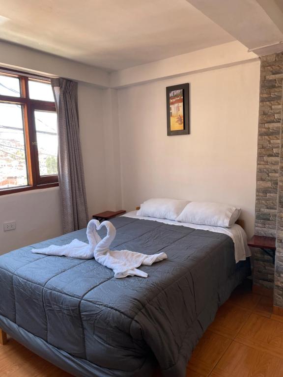 un dormitorio con una cama con una toalla de cisne en Big Vacation Hostel, en Cusco