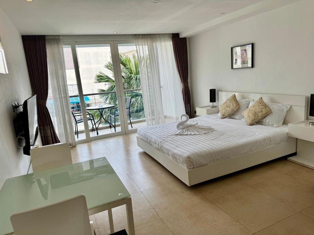1 dormitorio con cama, mesa y balcón en Centara Avenue Residences 1 bedroom Pattaya Center near beach shopping mall en Pattaya Central