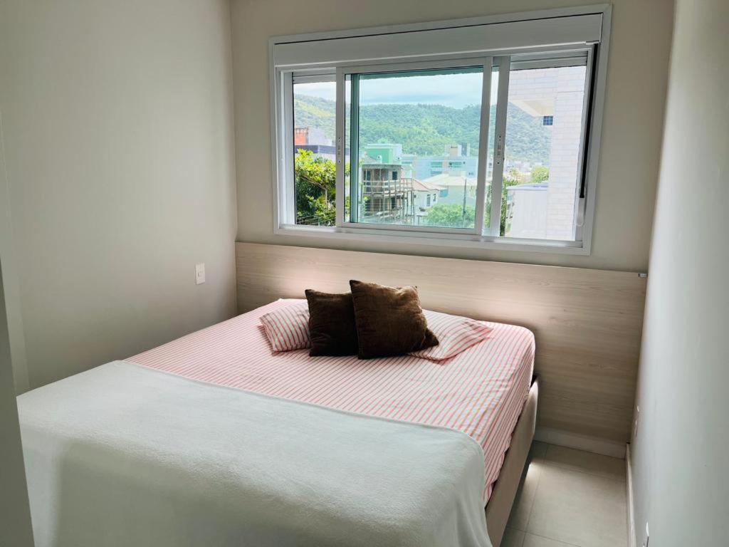 a small bedroom with a bed with a window at Apartamento na Praia de Palmas com garagem in Governador Celso Ramos