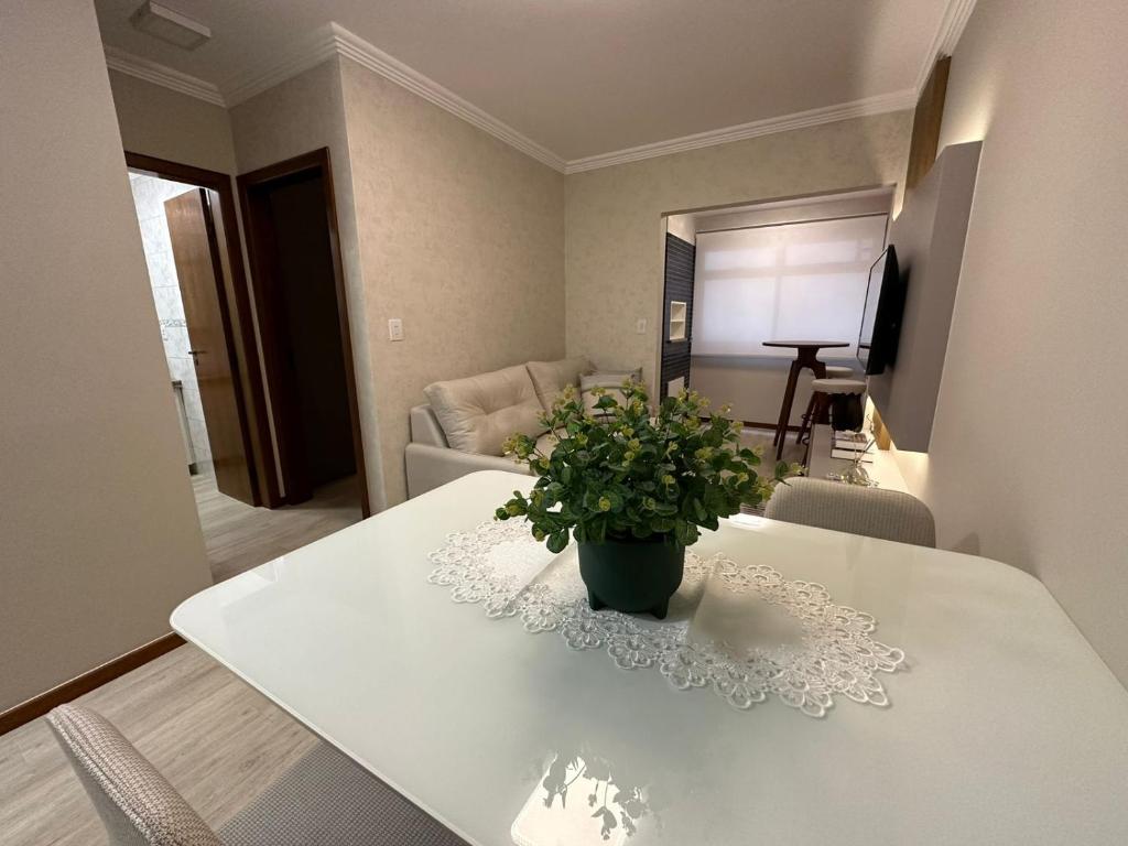 a white table with a potted plant on it in a living room at Apto super luxo beira mar Capão da Canoa in Capão da Canoa