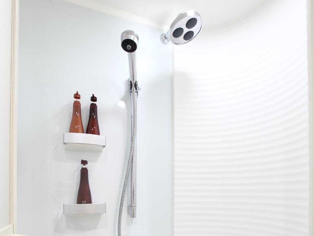a shower with a shower head and bottles on the wall at Tokyu Stay Kamata - Tokyo Haneda in Tokyo