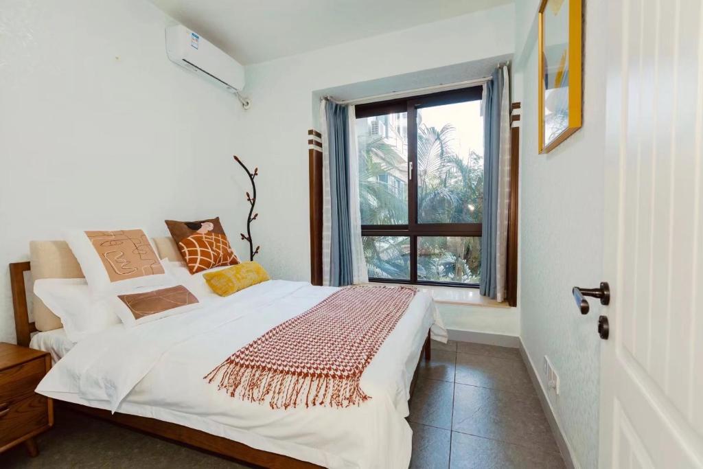 a white bedroom with a bed and a window at Sunny Apartment, minutes to beach in Shuijiao