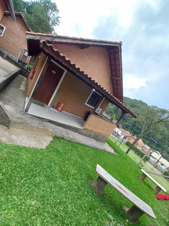 a house with a bench in front of it at Chalés lima in Monte Verde