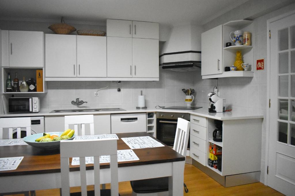 a kitchen with white cabinets and a table and chairs at Bella's Hideaway in Ponta Delgada