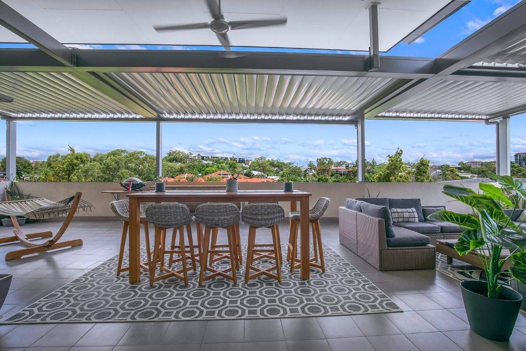 - un salon avec une table et des chaises sur une terrasse dans l'établissement Top of Taringa Penthouse with Sweeping Views, à Brisbane