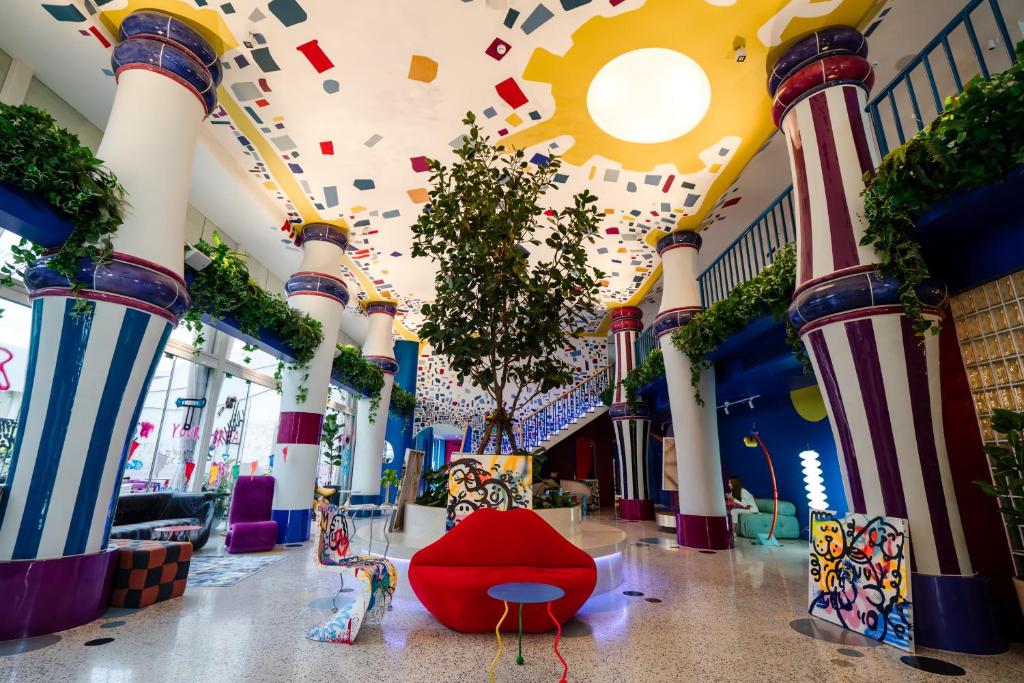 un pasillo con columnas y una silla roja en un edificio en The Fig Lobby en Bangkok