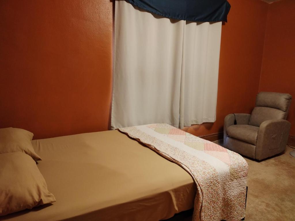 a bedroom with a bed and a chair and a window at Cool and affordable apartment Galesburg in Galesburg