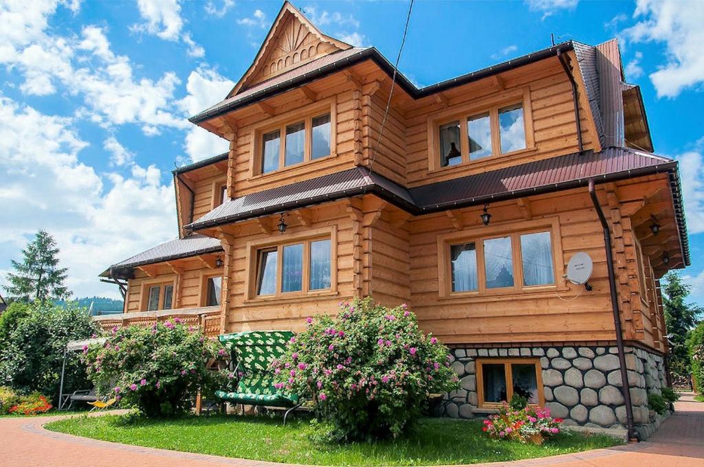 ein Holzhaus mit einer Bank davor in der Unterkunft Dom Wypoczynkowy Anetka in Białka Tatrzańska