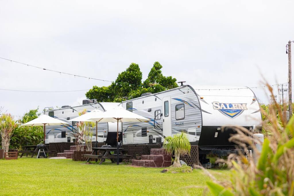 an rv parked in a yard with tables and umbrellas at Natural farm Zanpa -SEVEN Hotels and Resorts- in Yomitan