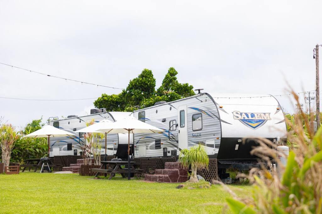 uma carrinha estacionada num quintal com mesas e guarda-chuvas em Natural farm Zanpa -SEVEN Hotels and Resorts- em Yomitan