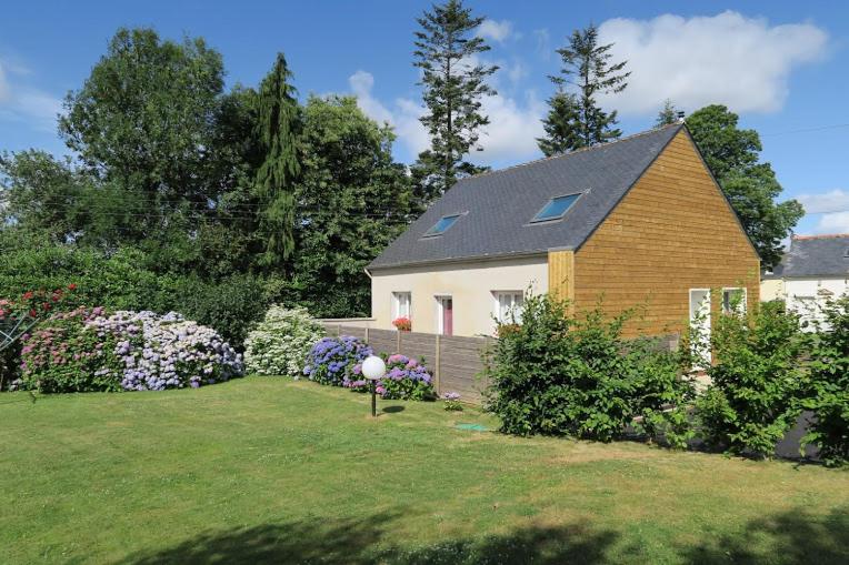 una casa en un patio con flores y un jardín en Kerhervé, en Cléden-Poher