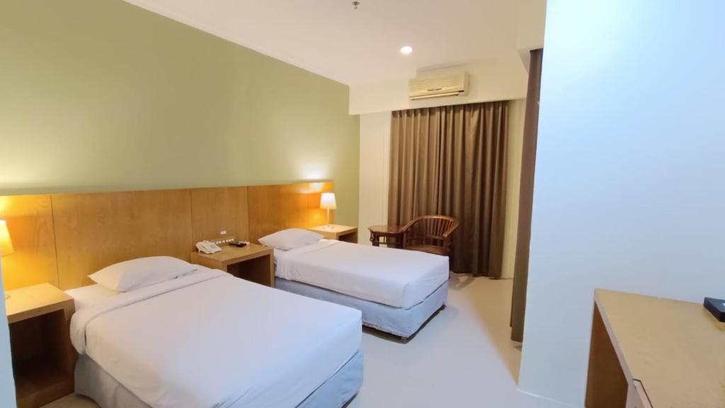 Habitación de hotel con 2 camas y escritorio en Hotel Wisata, en Palembang