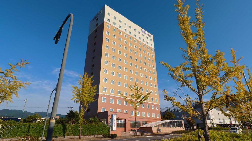 un grand bâtiment avec un arbre devant lui dans l'établissement Toyoko Inn Tenri Ekimae, à Tenri