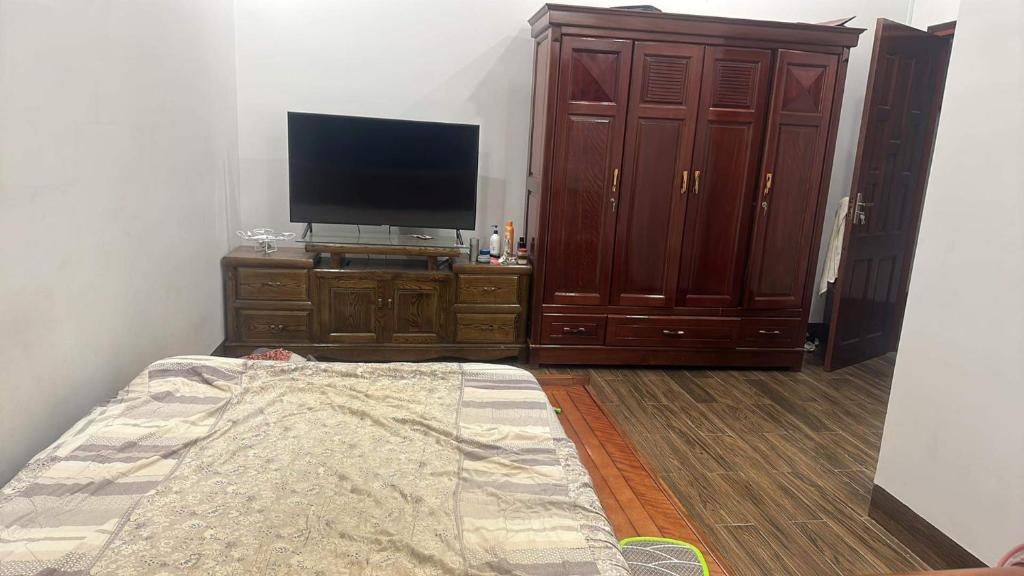 uma sala de estar com uma televisão e uma cómoda com uma cama em B house em Thôn Hòa Ða
