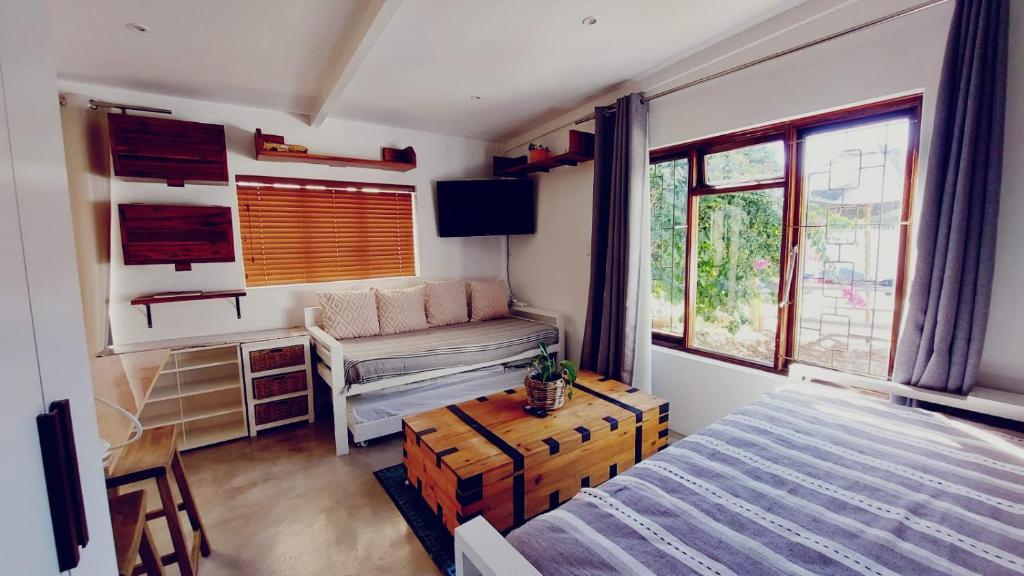 a bedroom with a bed and a desk and windows at Private modern cottage in St Francis with big secure garden in St Francis Bay