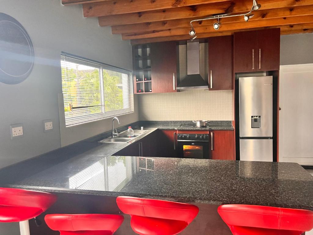 a kitchen with a counter and red stools in it at Number 87 in East London