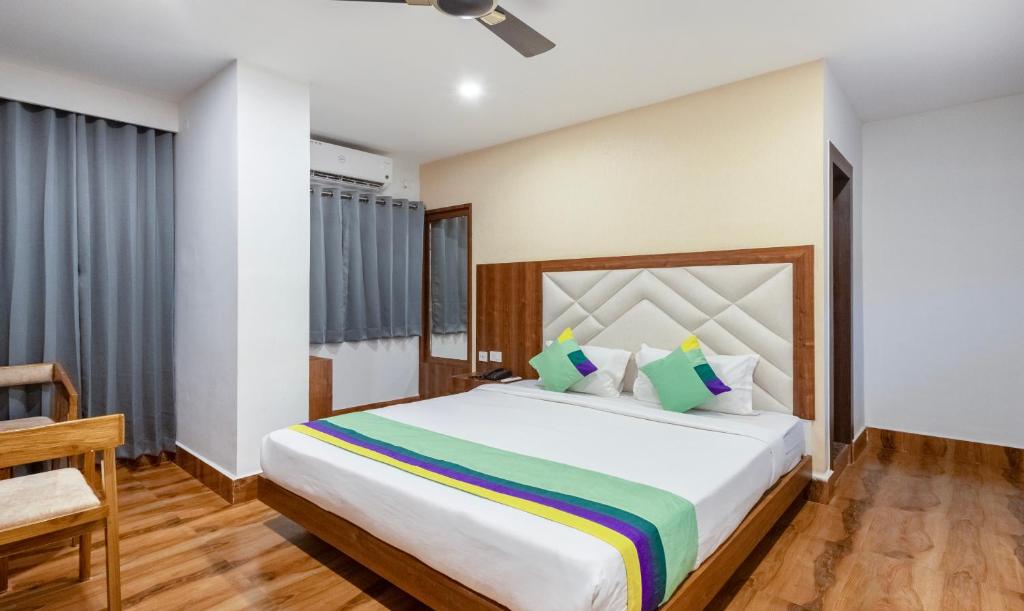 a bedroom with a large bed and a chair at Treebo Trend Royal Palace, Zoo Road in Dispur