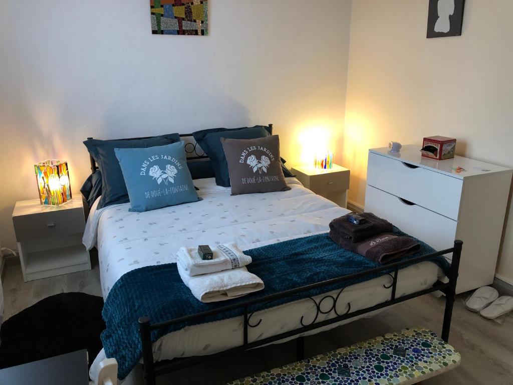 1 dormitorio con 1 cama con almohadas y toallas azules en Chez Annie, en Doué-la-Fontaine