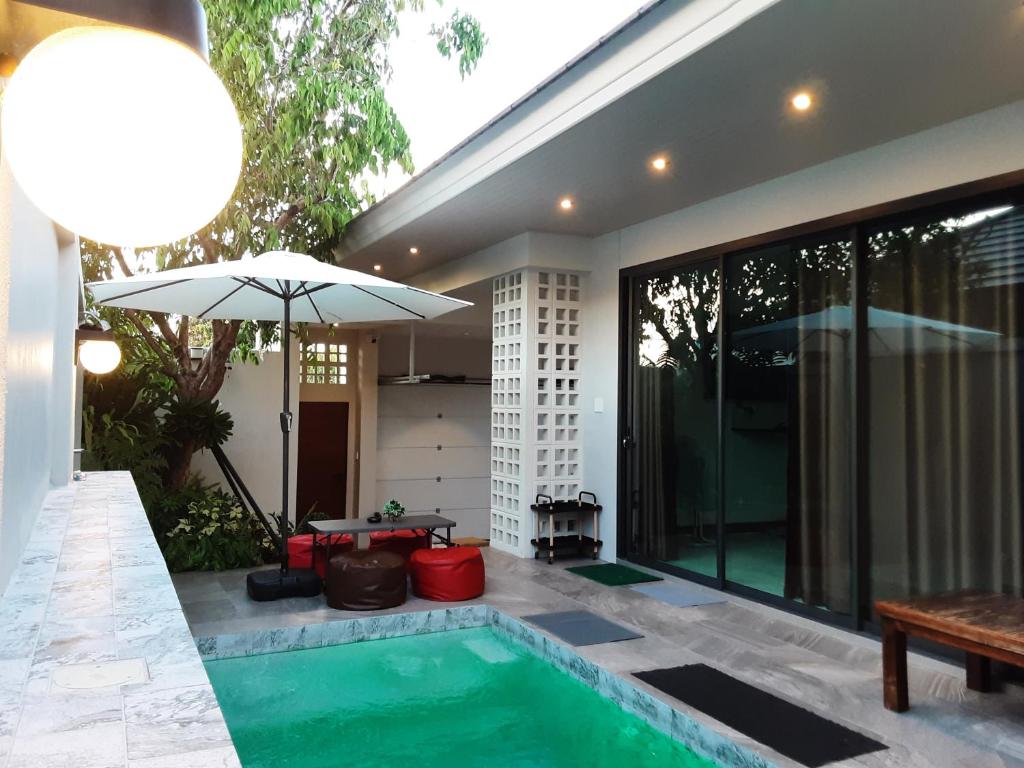 einen Pool mit Sonnenschirm neben einem Haus in der Unterkunft Paul Pool Villa Pattaya in Bang Sare