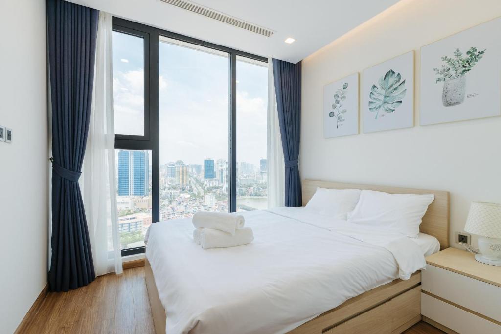 a bedroom with a white bed with a large window at Royal Serviced apartment Vinhomes Metropolis in Hanoi