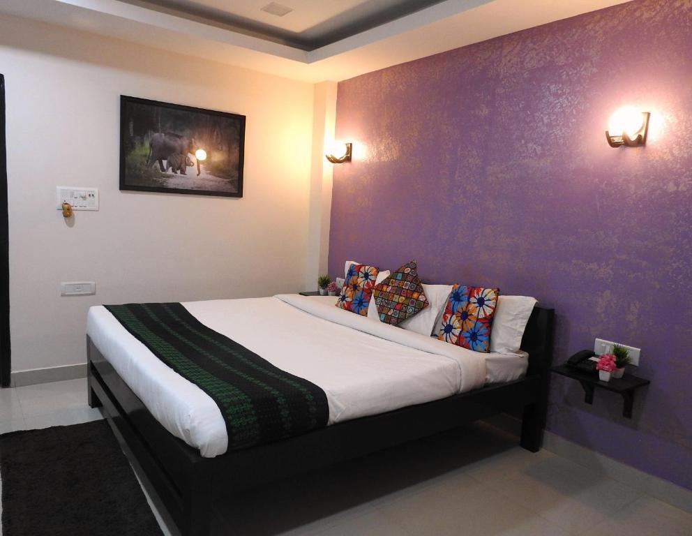 łóżko w pokoju z fioletową ścianą w obiekcie Kohua Bon - Kaziranga w mieście Hatikhuli
