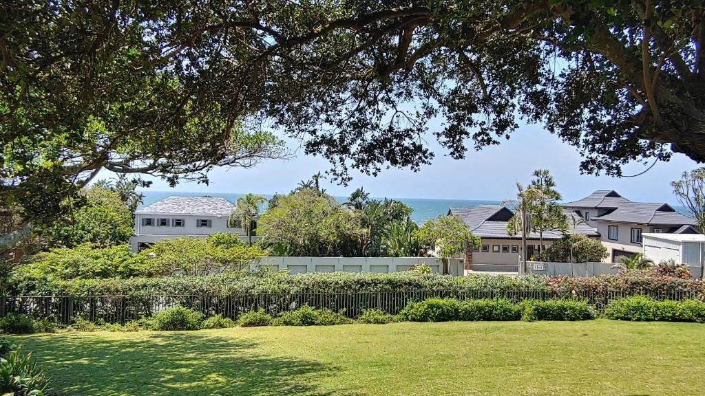 a yard with houses and the ocean in the background at Kerynmere, 114 Nkwazi Drive, Zinkwazi Beach in Zinkwazi Beach