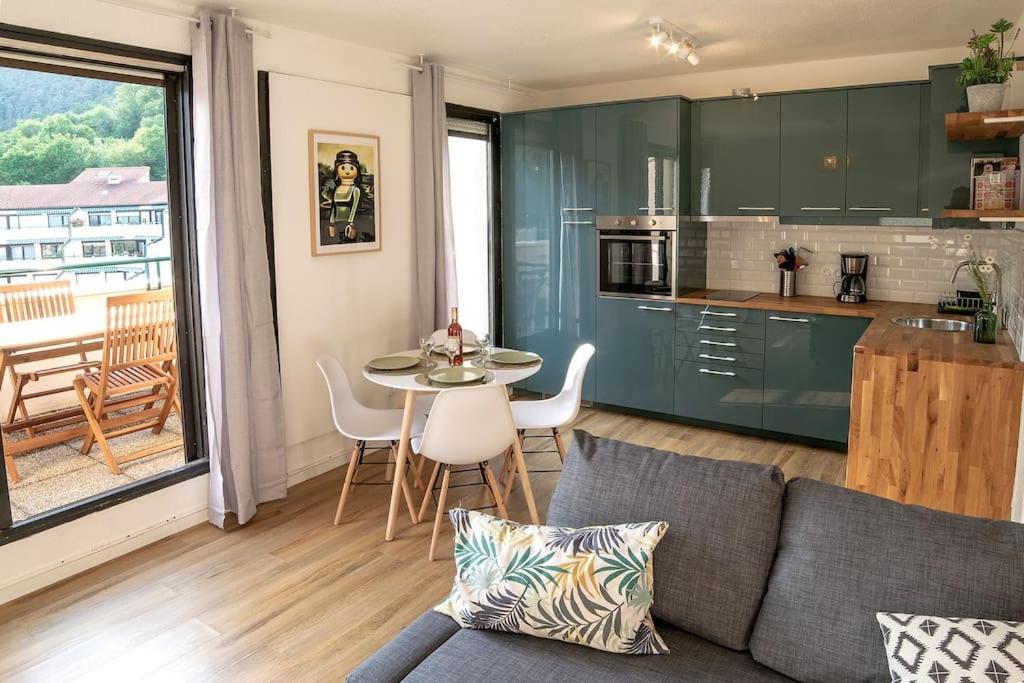 een woonkamer met een bank en een tafel en een keuken bij Ville & Nature, Belle Vue avec Piscine in Chamalières
