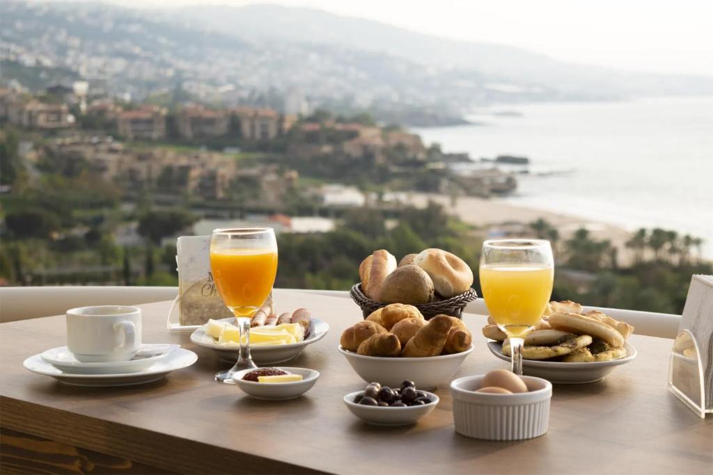 una mesa con alimentos para el desayuno y vasos de zumo de naranja en Sands Hotel en Jbeil