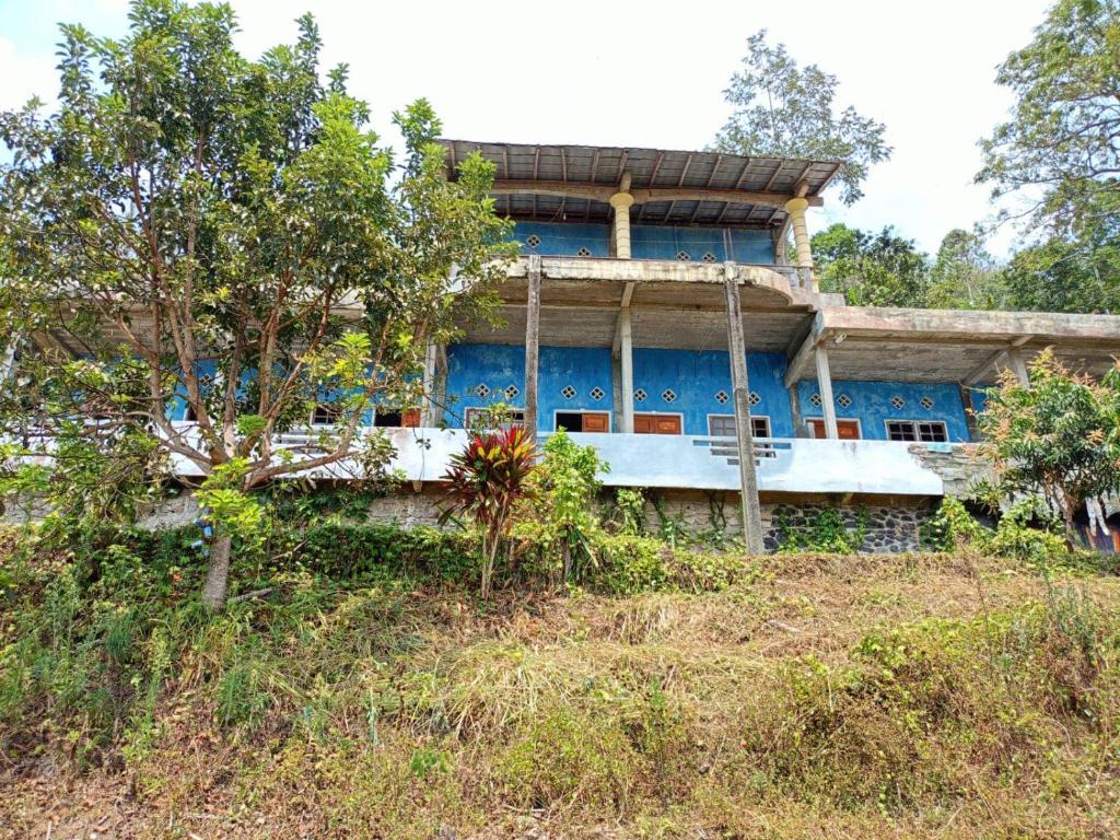 a blue building on top of a hill with trees at OYO 93241 Hotel Puri Azzura Danau Ranau in Jepara