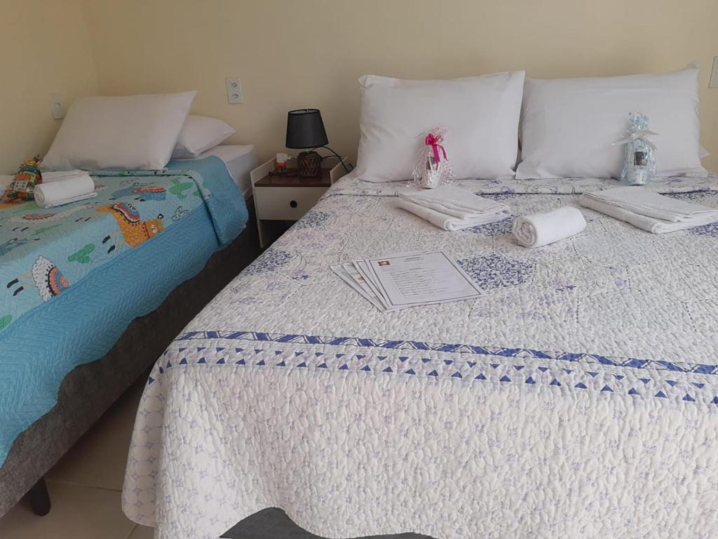 um quarto com duas camas com lençóis brancos e um livro em Aconchego da Vovó em Araruama