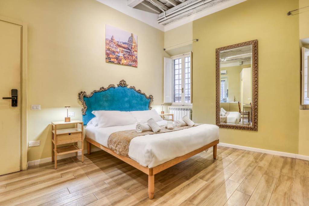 een slaapkamer met een bed met een blauw hoofdeinde en een spiegel bij Domus Orbitelli in Rome