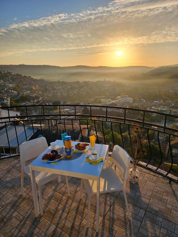 a table with food and drinks on a balcony with the sunset at TOP SKY VIEW - Studio Panorama in Veliko Tŭrnovo