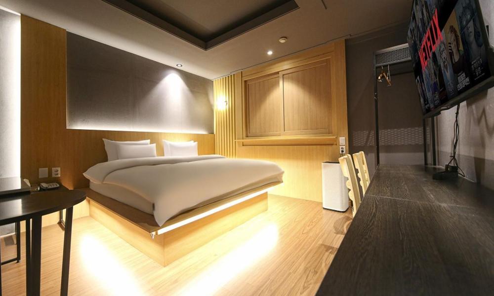 a bedroom with a large white bed and a table at Hotel Feel Green in Goyang