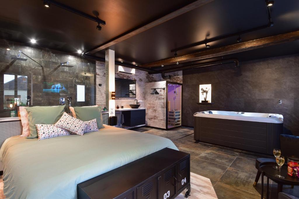 1 dormitorio con 1 cama grande y bañera en La Forge By CV - Jacuzzi, Sauna, plat repas et petit déjeuner en Eppe-Sauvage