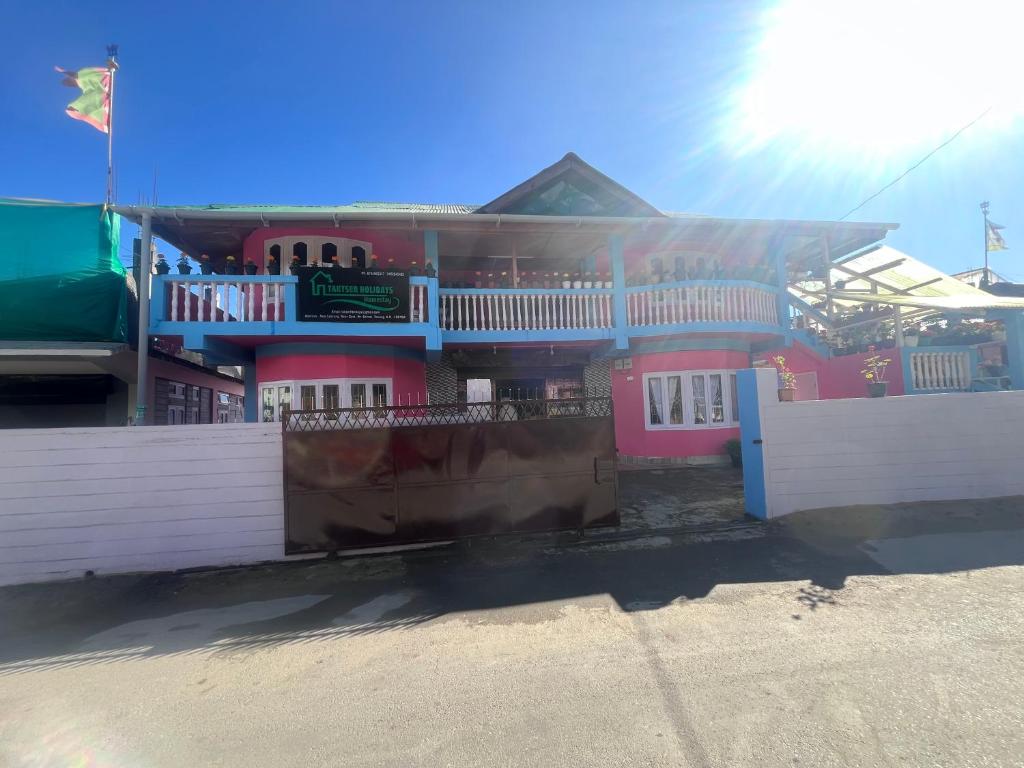 une maison rose avec une clôture blanche devant elle dans l'établissement Taktserholidays, à Tawang