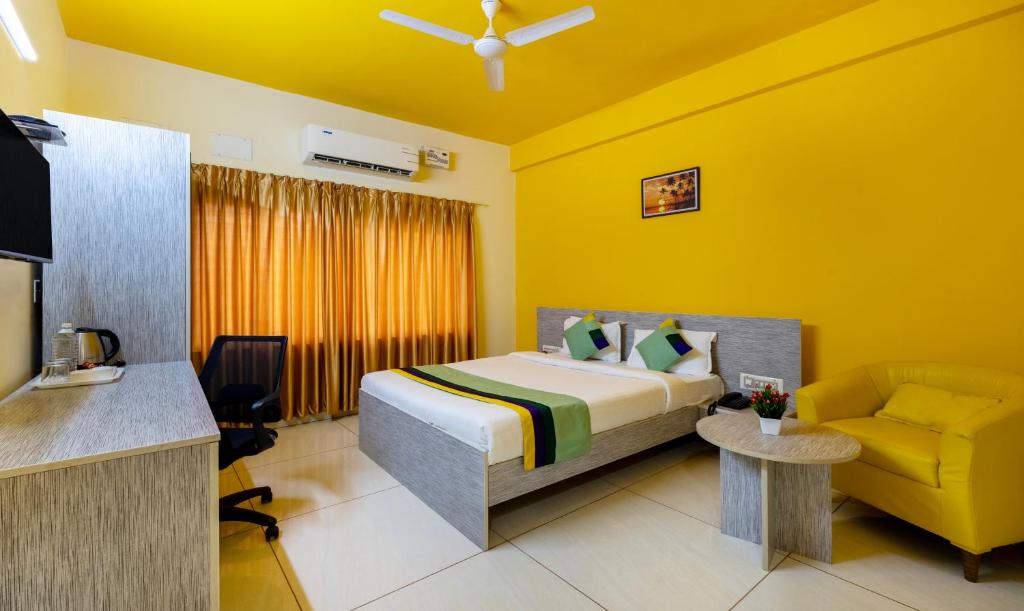 een hotelkamer met een bed en een stoel bij Treebo Trend Four Seasons in Narasimharaja Puram