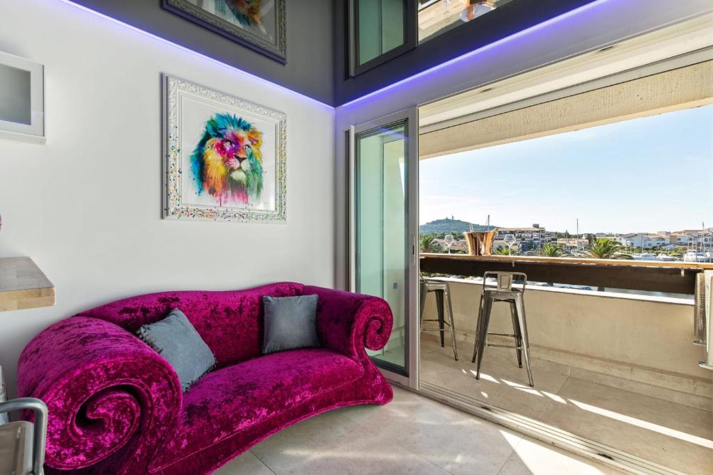 - un canapé violet dans une chambre avec une grande fenêtre dans l'établissement Lux'art Port Nature, au Cap d'Agde