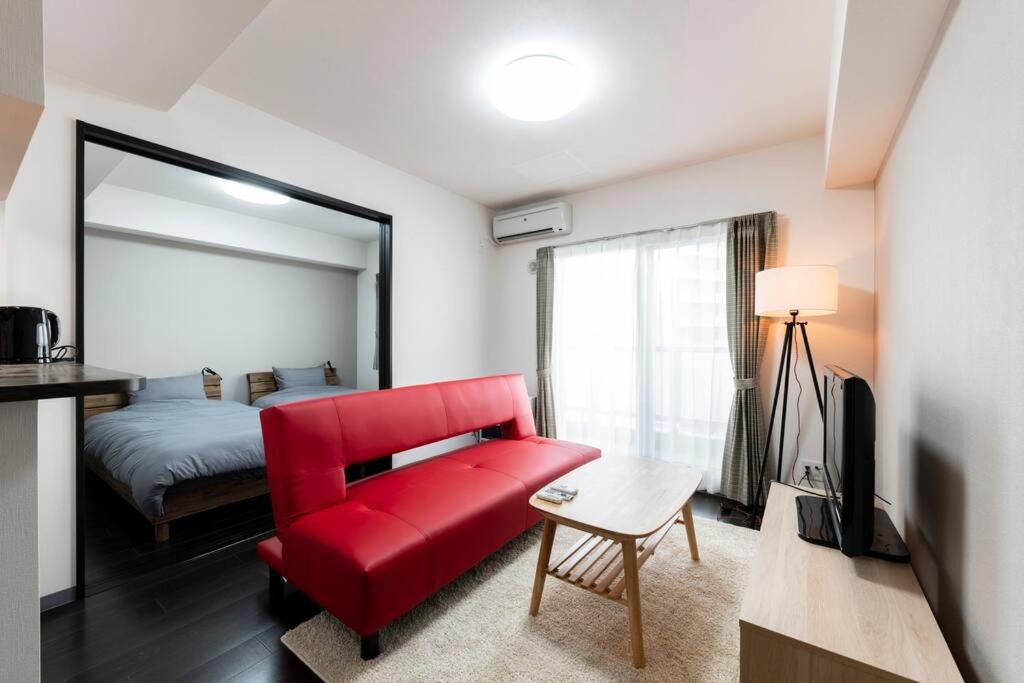 uma sala de estar com um sofá vermelho e uma cama em STELLAR em Ōdōri