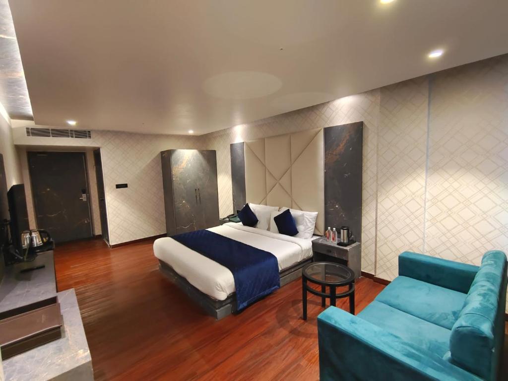 1 dormitorio con 1 cama grande y 1 sofá azul en The Emerald Hotel & Siya Milan Banquets en Muzaffarpur
