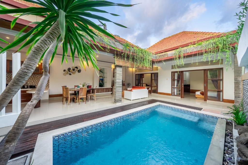 a villa with a swimming pool in front of a house at De Gani in Seminyak