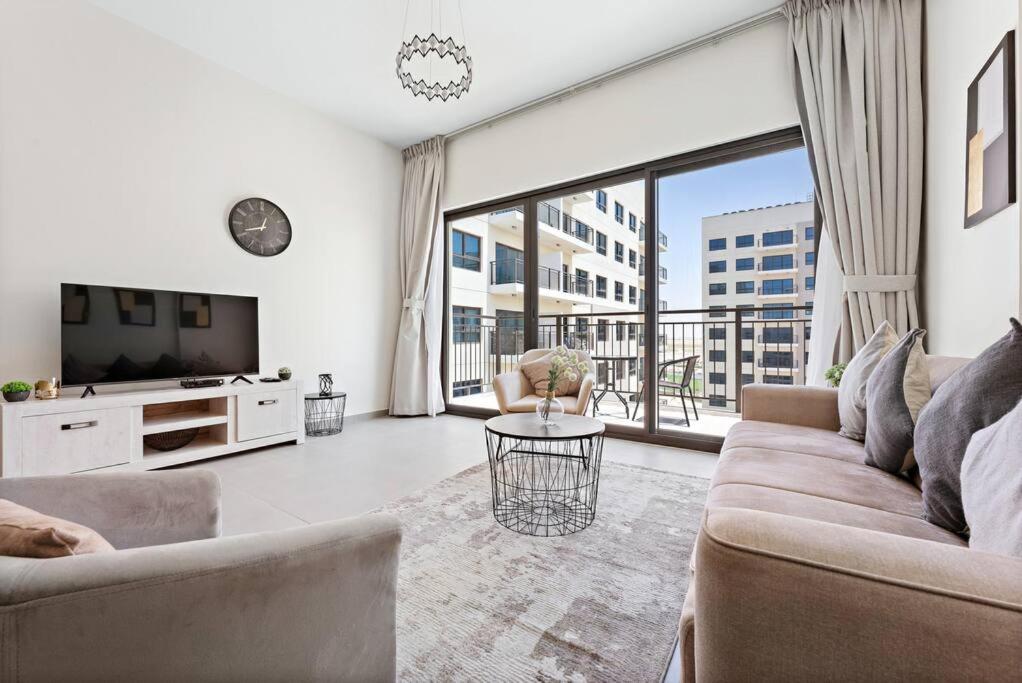 a living room with a couch and a tv at StoneTree - Spacious 2BR Apartment in Golf Views Block A in Dubai