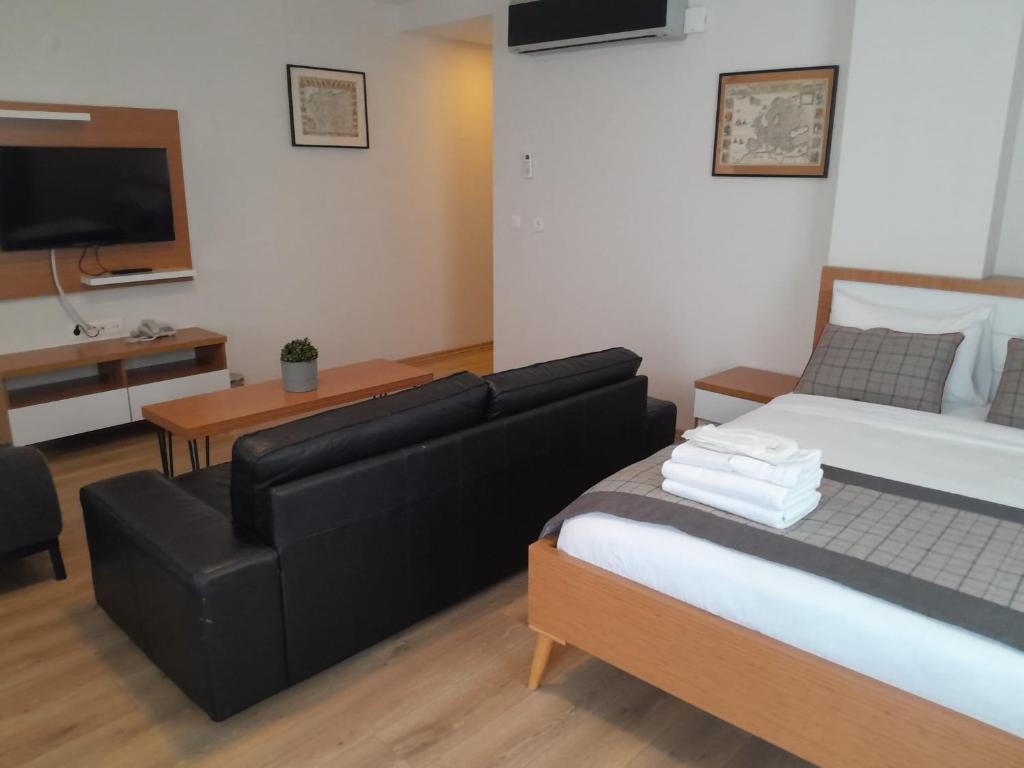 a bedroom with a bed and a couch and a television at Del Puerto Hotel in Aliağa