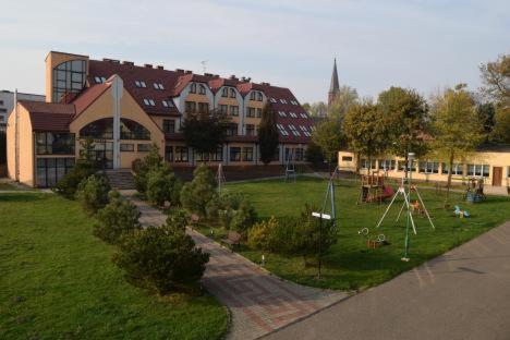 uma escola com um parque infantil em frente a um edifício em Politechnika Warszawska Ośrodek Wypoczynkowy em Sarbinowo