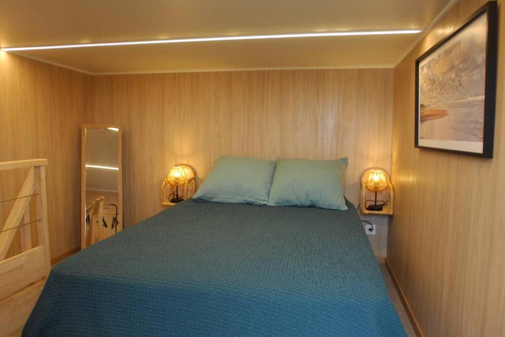 a bedroom with a bed and two lights on the wall at Tiny house proche de Morgat in Crozon