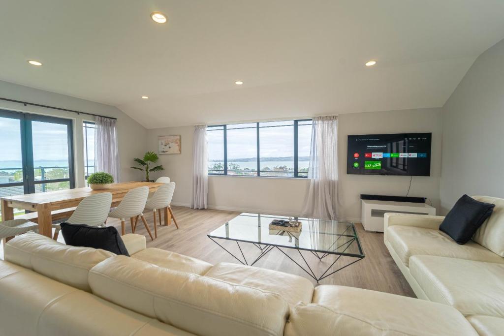 a living room with a white couch and a table at Family Friendly Oceanview Howick Home - Pets+ in Auckland