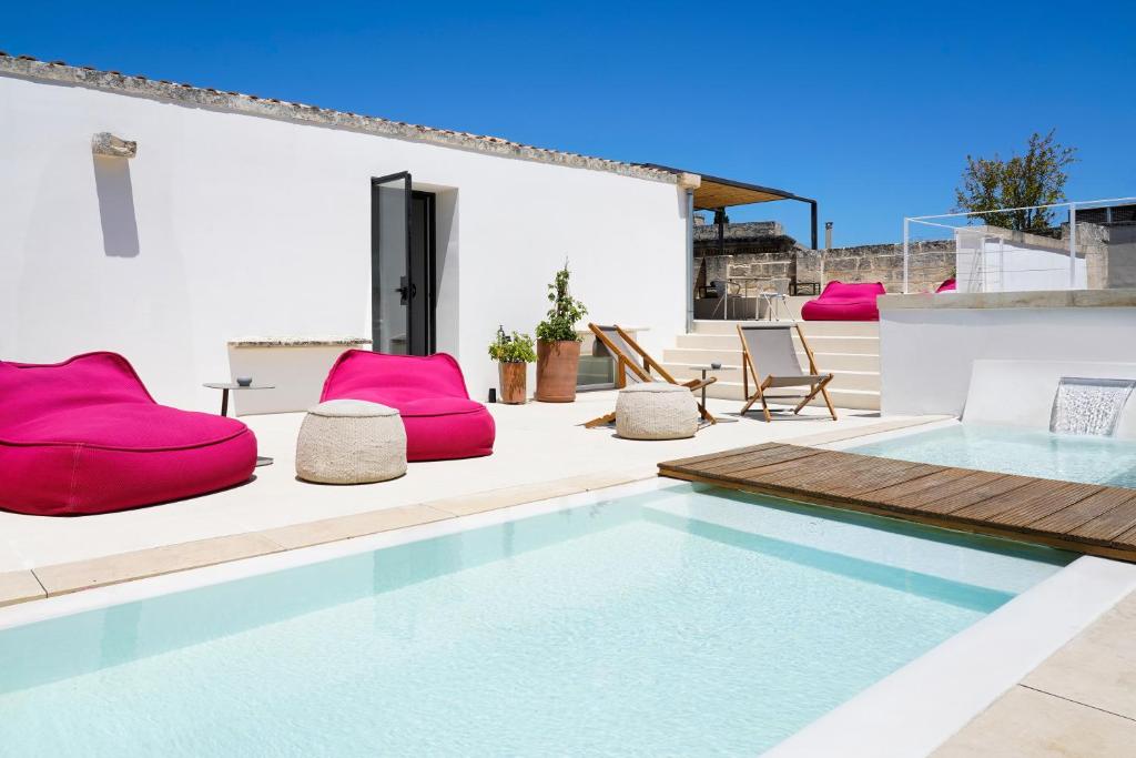 a swimming pool with pink chairs on a patio at Palazzo De Noha - Boutique Hotel in Lecce