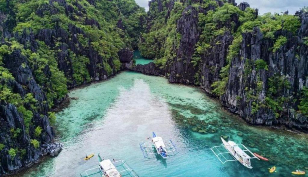 Trois bateaux dans l'eau d'une rivière arborée dans l'établissement Royal Duchess Pension, à Puerto Princesa