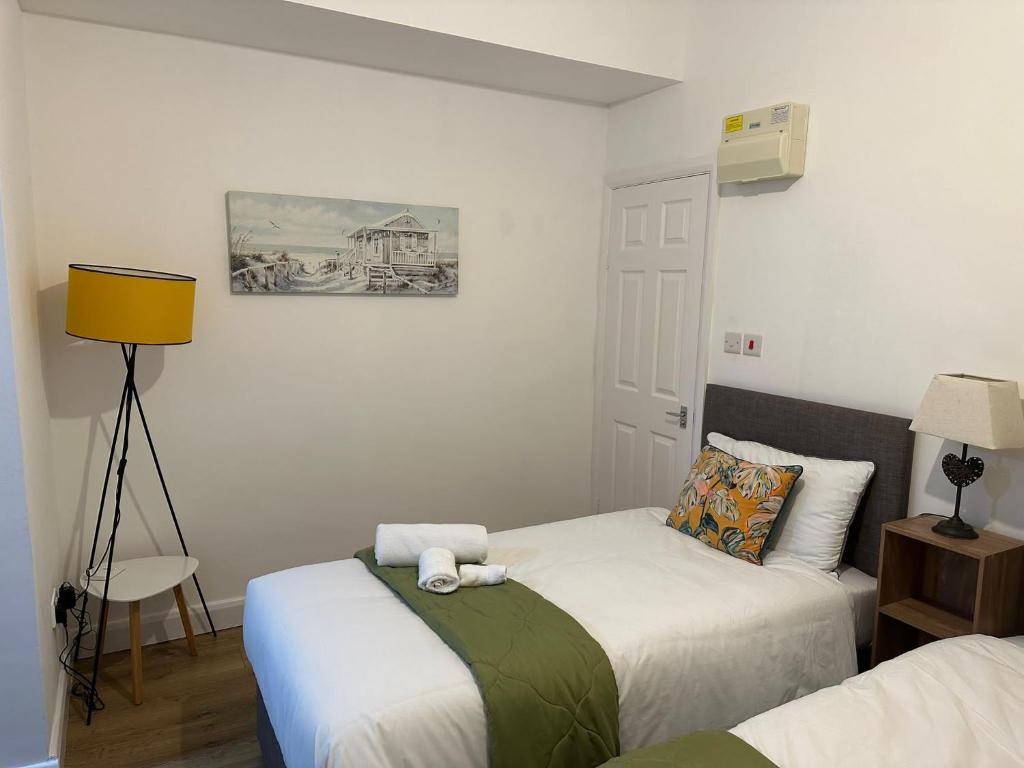 a bedroom with two beds and a yellow lamp at Delightful Delta-Studio Apt Walk-2Leeds city WiFi in Leeds